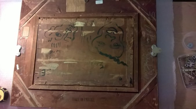 Preparing 'The Moon Worshipper' for hanging. Dillon has decorated the reverse of the panel with outline faces. 